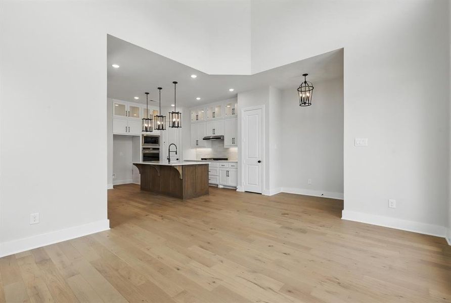 Kitchen featuring glass insert cabinets, a kitchen breakfast bar, white cabinets, a chandelier, and recessed lighting
