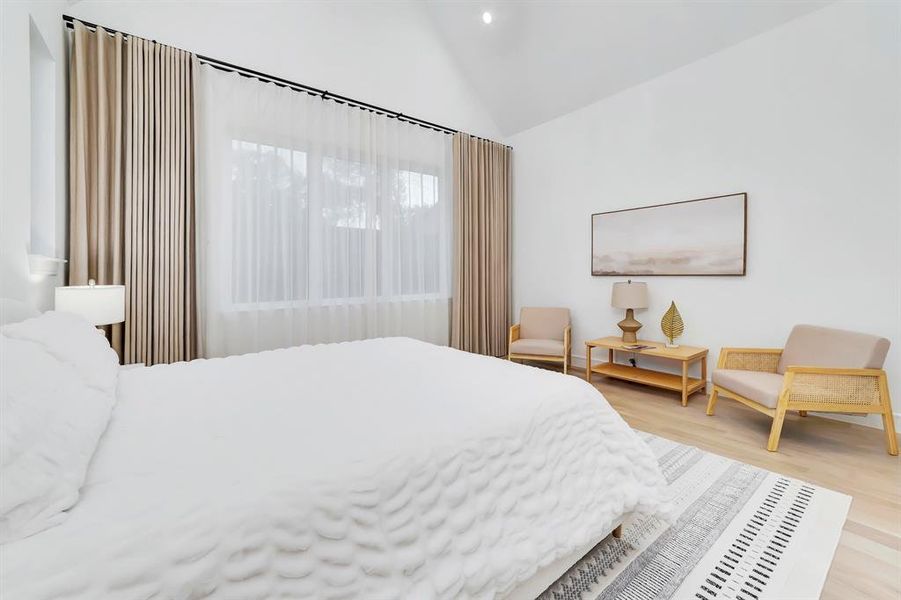 Bedroom featuring vaulted ceiling and light wood-style flooring Bedroom featuring vaulted ceiling and light wood-style flooring