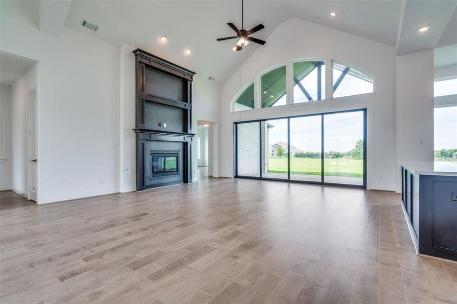 Unfurnished living room featuring high vaulted ceiling, ceiling fan, and light hardwood / wood-style floors