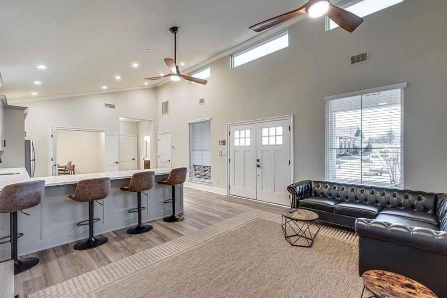 Living room with a ceiling fan, high vaulted ceiling, and light wood-style floors Living room with a ceiling fan, high vaulted ceiling, and light wood-style floors