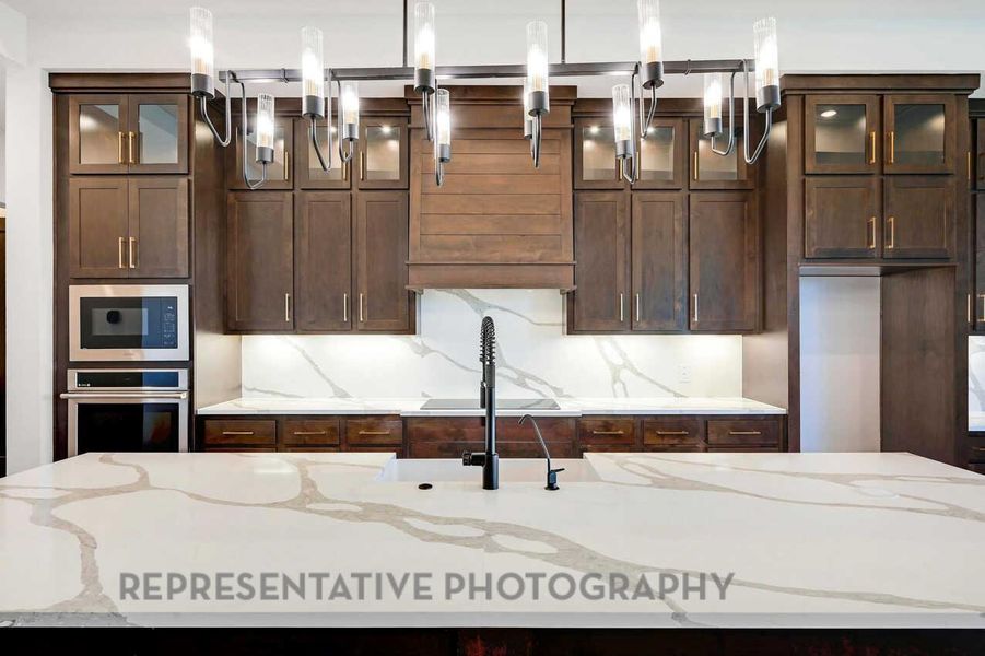 Kitchen featuring glass insert cabinets, light stone counters, and appliances with stainless steel finishes Kitchen featuring glass insert cabinets, light stone counters, and appliances with stainless steel finishes