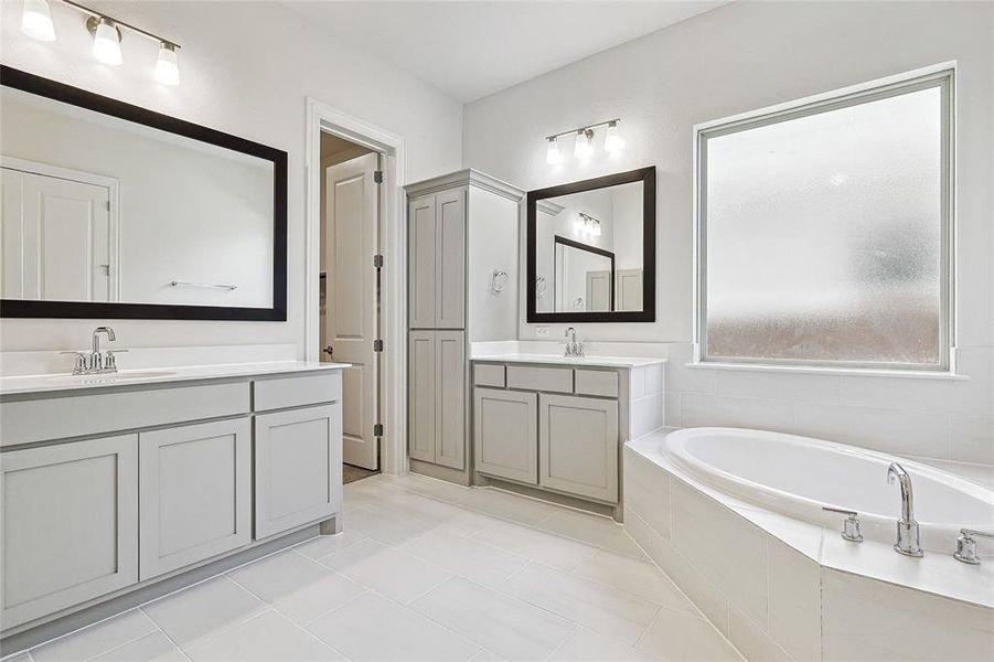 Bathroom featuring vanity, tile patterned floors, and a relaxing tiled tub