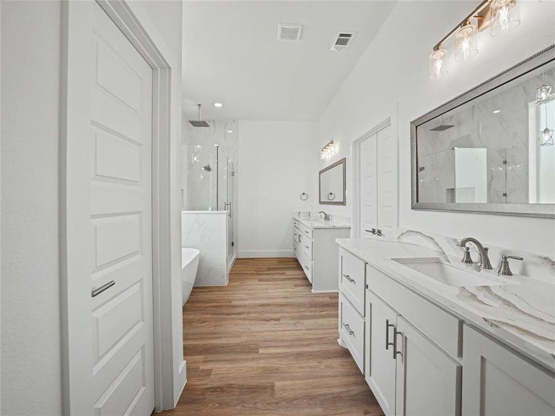 Spacious bathroom featuring wood-finish flooring, a freestanding tub, and a glass-enclosed shower with a rainfall showerhead