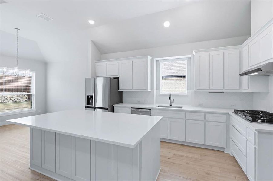 Light and bright kitchen with oversized island, stainless steel appliances, and ample cabinet space.