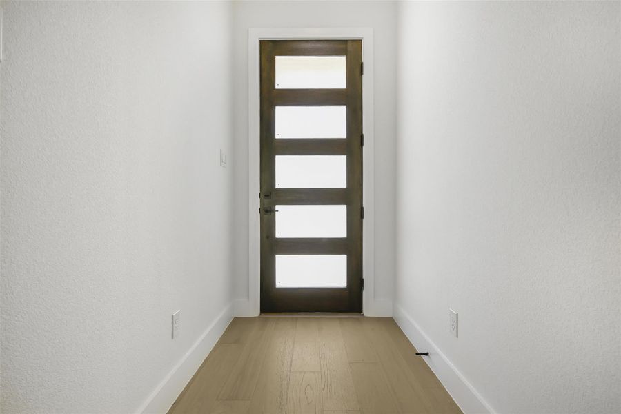 Entryway with light wood-style flooring and a textured wall