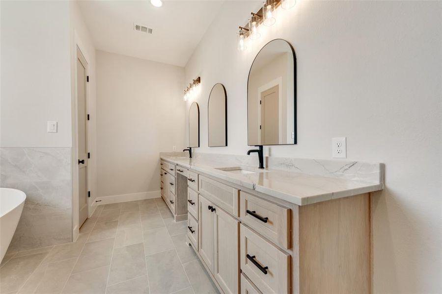 Bathroom with tile flooring, dual vanity, and a washtub