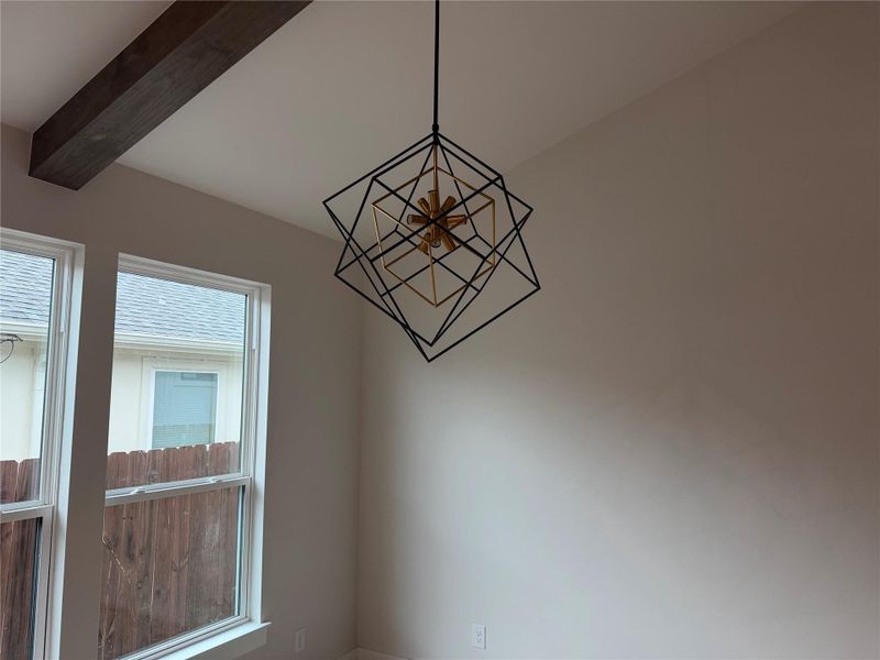 Accentuated by a striking geometric light fixture, this room features a rustic exposed beam.