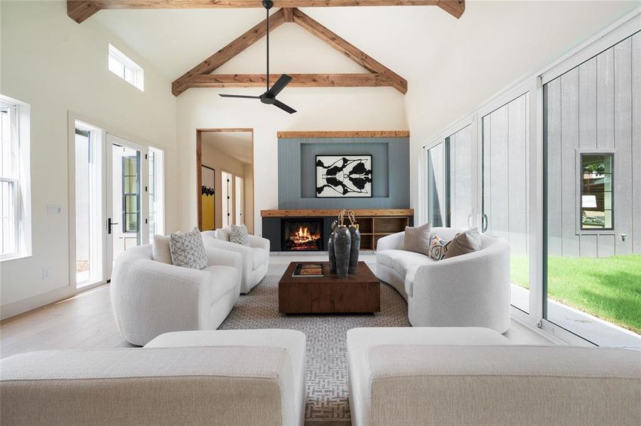 Living room with high vaulted ceiling, beamed ceiling, light wood-type flooring, and ceiling fan