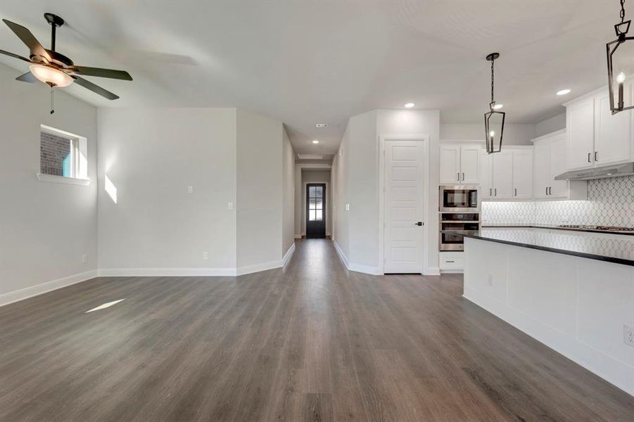 Unfurnished living room featuring dark wood-style flooring, a ceiling fan, and recessed lighting