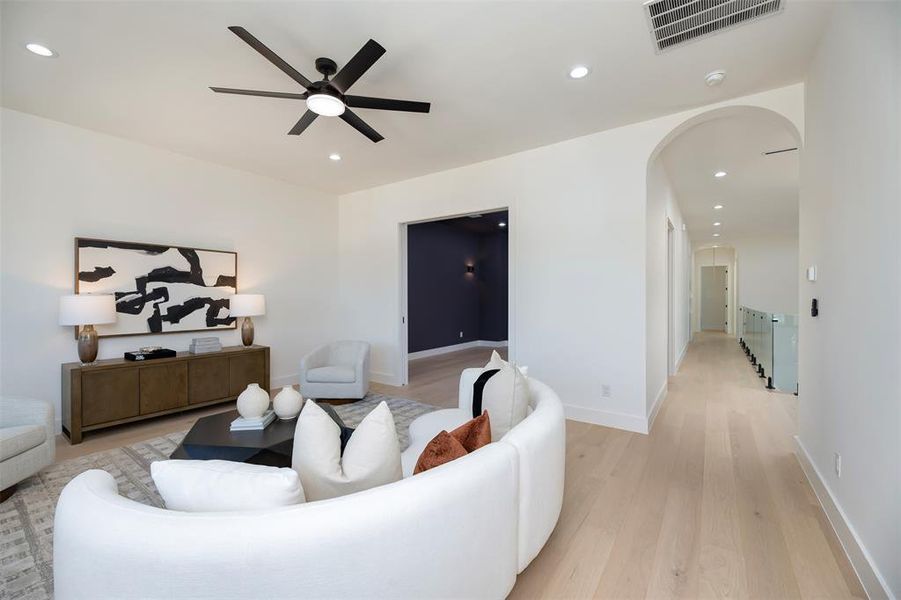 Living room with recessed lighting, light wood finished floors, arched walkways, and a ceiling fan Living room with recessed lighting, light wood finished floors, arched walkways, and a ceiling fan