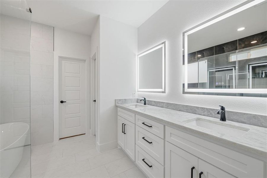 Full bath with double vanity, light tile patterned floors, a freestanding tub, and a shower