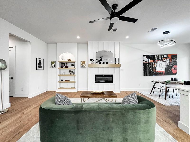 Living area featuring ceiling fan, baseboards, a large fireplace, light wood-type flooring, and recessed lighting