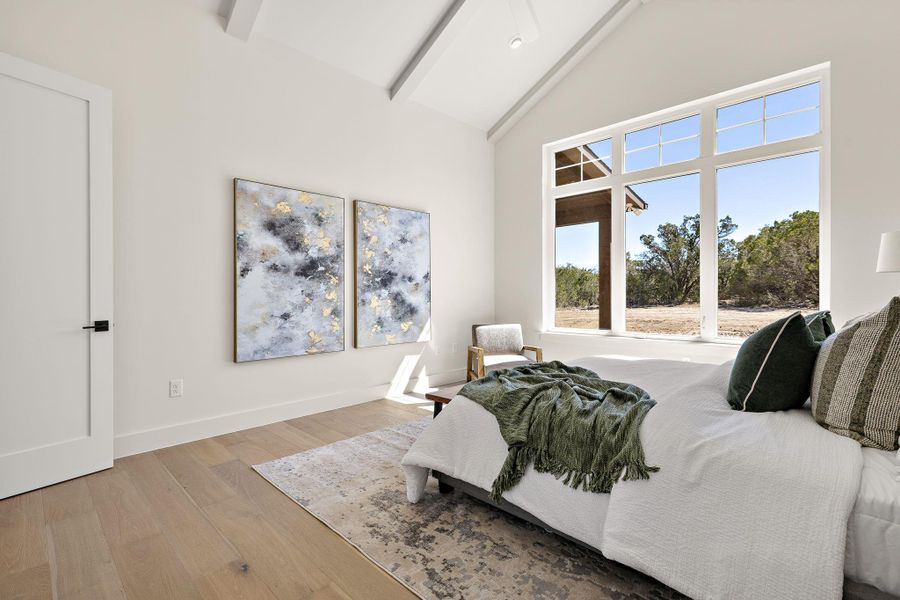 Bedroom with high vaulted ceiling, wood finished floors, beam ceiling, and baseboards