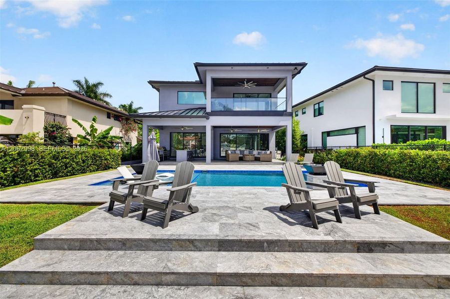 View from the new concrete dock and seawall to the Salt chlorinated pool w/ water features, LED color changing light, sun shelf with umbrella hole and in water stools. Stone decking surrounds the pool