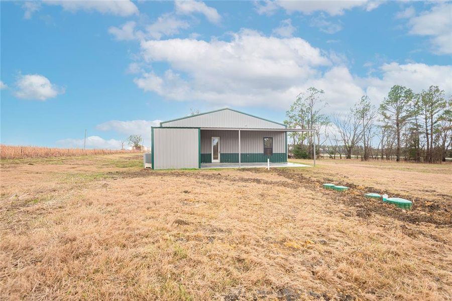 Back of house featuring an outbuilding, an outdoor structure, and a yard