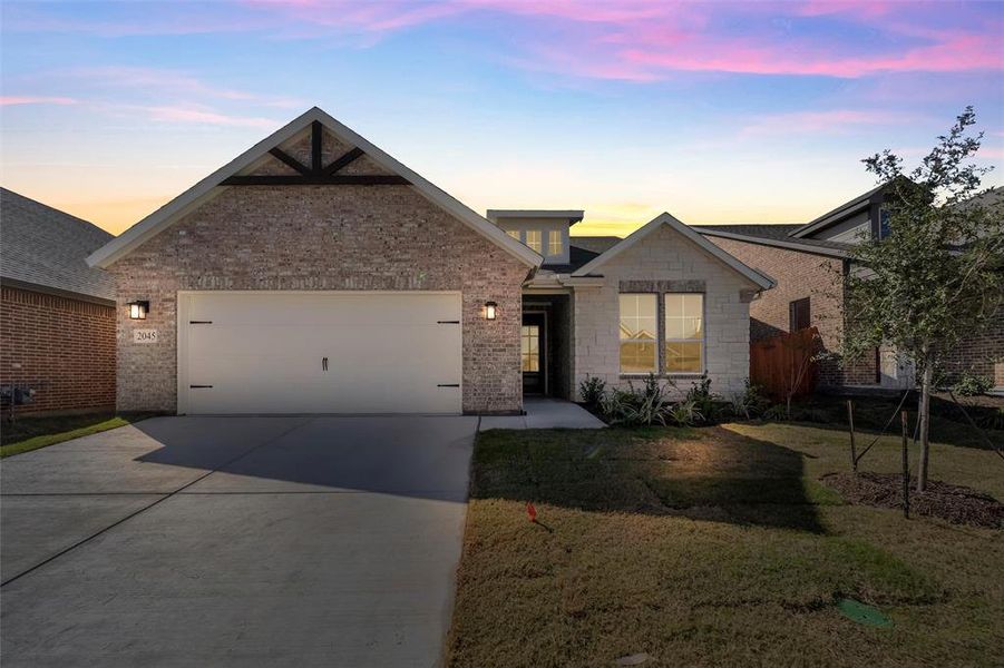 Traditional-style house with concrete driveway, a lawn, a garage, and brick siding