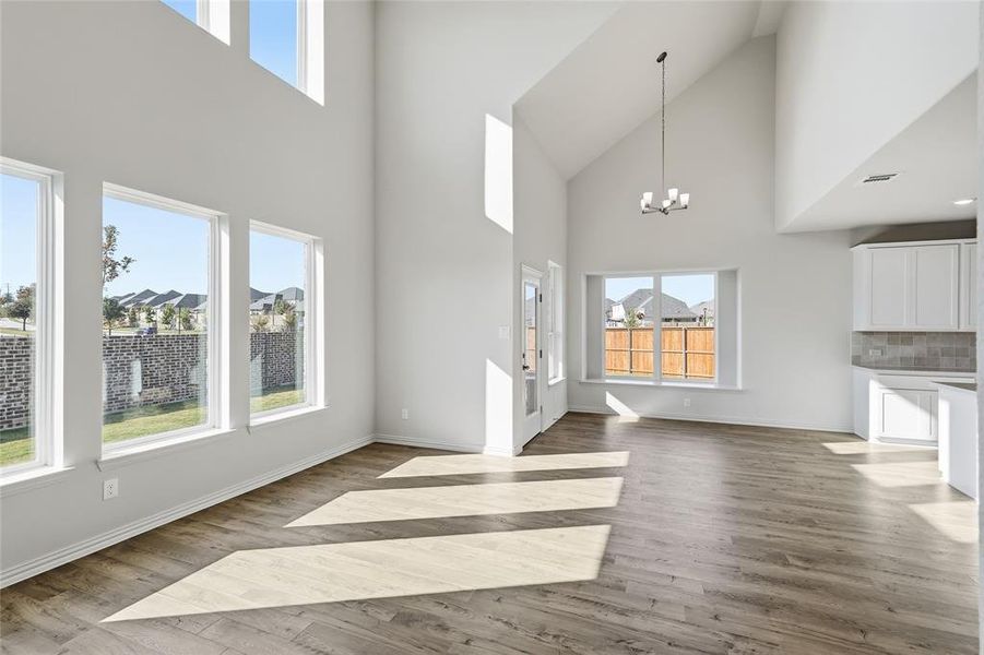 Unfurnished living room with a chandelier, a high ceiling, and light wood-type flooring
