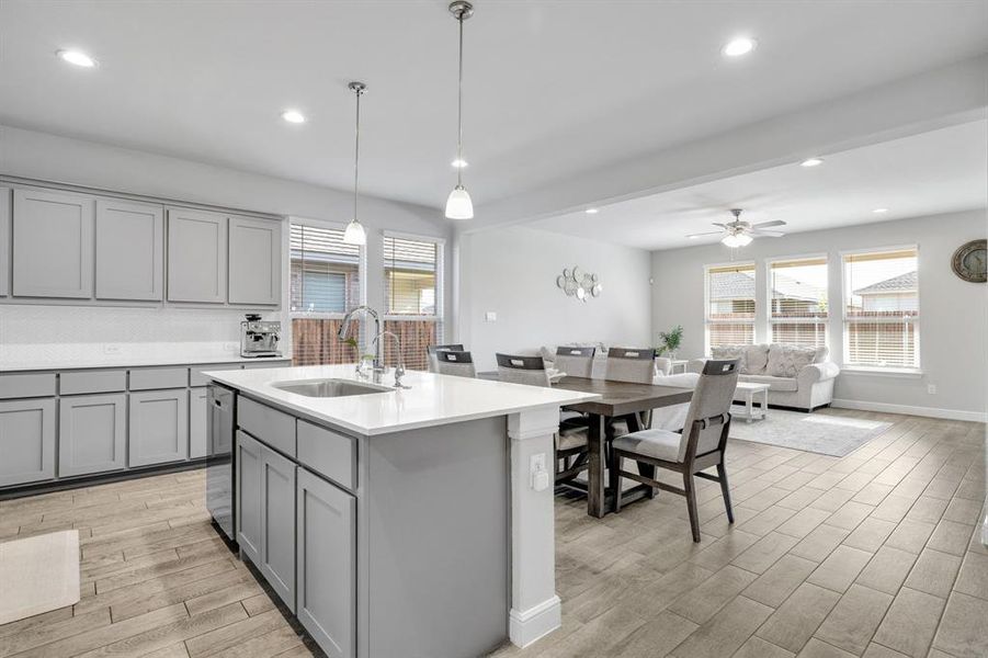 Kitchen featuring gray cabinets, recessed lighting, light wood finished floors, light countertops, and a kitchen island with sink