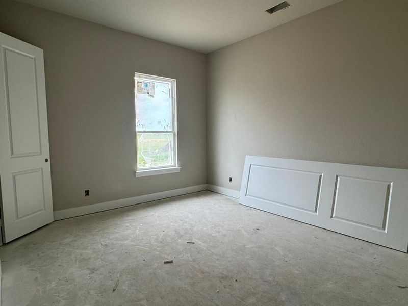 Neutral-toned room featuring a single window, white trim, and a panel door