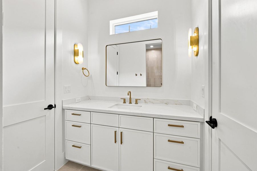Full bathroom with quartz countertops has direct access to the bedroom and game room.