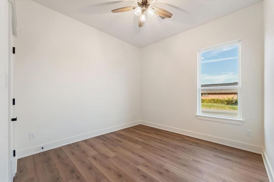 Secondary bedroom features no carpet, a ceiling fan & a walk-in closet.