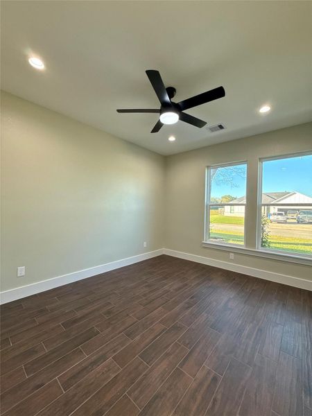 This room features hardwood floors, neutral walls, and large windows providing ample natural light. A modern ceiling fan is centrally installed, enhancing comfort and style. This room features hardwood floors, neutral walls, and large windows providing ample natural light. A modern ceiling fan is centrally installed, enhancing comfort and style.