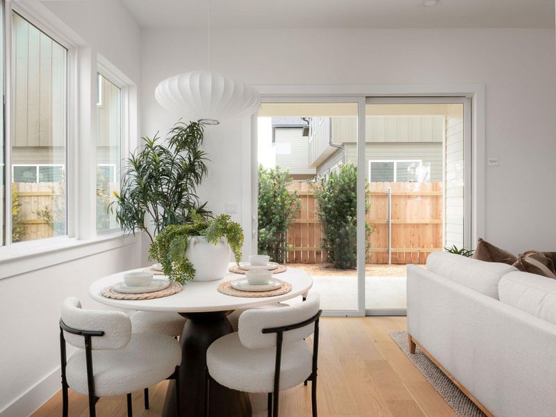 Natural light floods this dining area, featuring a contemporary light fixture and backyard access.