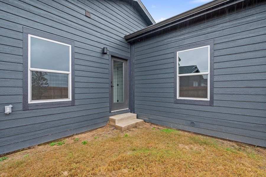 Doorway to property with a lawn