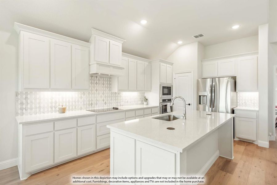 White kitchen with large center island, stainless steel appliances, patterned tile backsplash, and light wood floors