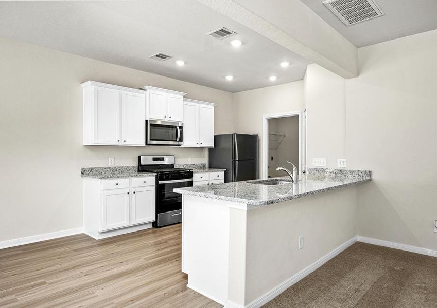 A kitchen with white cabinets and grey granite countertops.