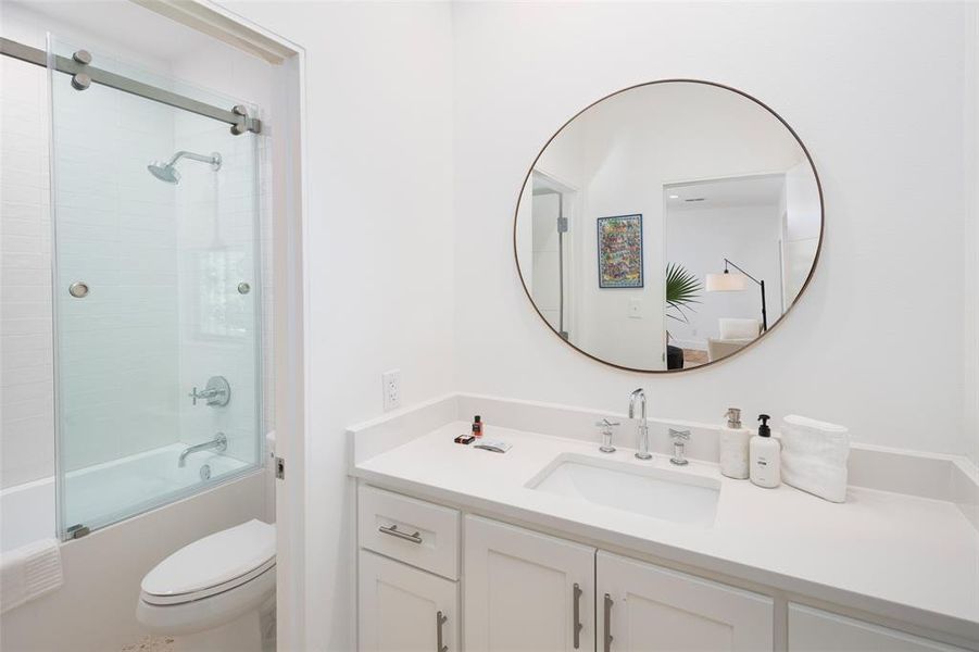 Full bathroom featuring vanity, bath / shower combo with glass door, and toilet Full bathroom featuring vanity, bath / shower combo with glass door, and toilet
