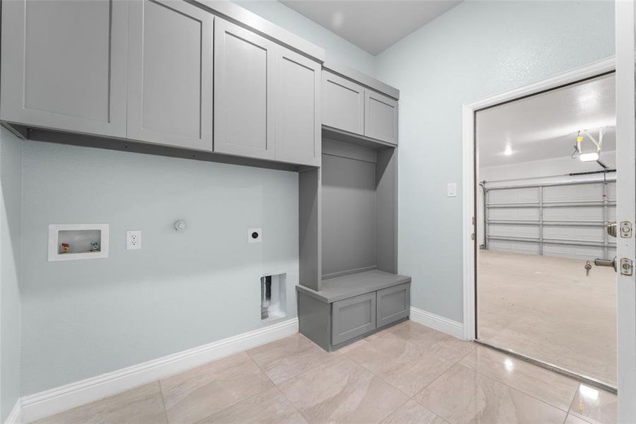 Laundry room with light tile patterned flooring, hookup for an electric dryer, gas dryer hookup, hookup for a washing machine, and cabinets