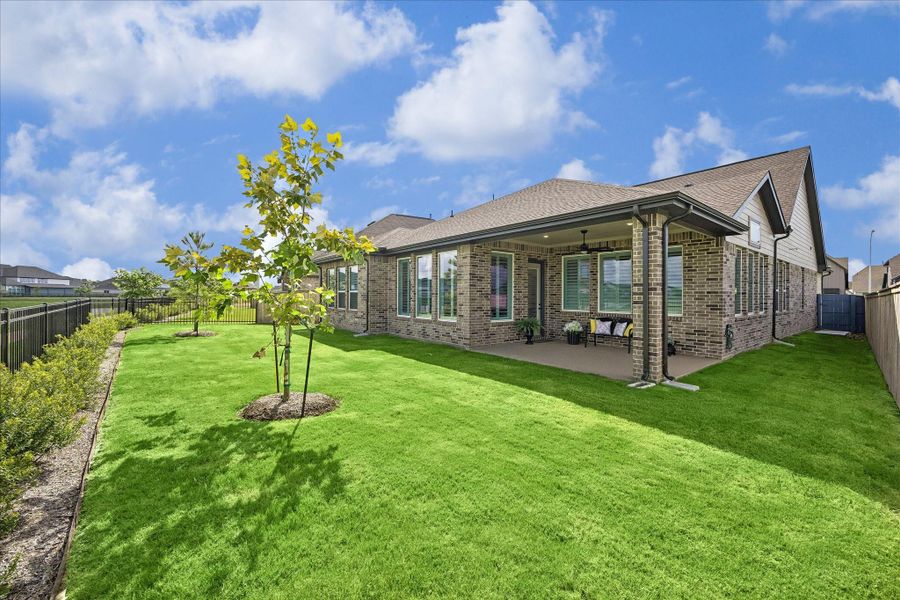 Backyard, patio, and side yard. Home features full home sprinkler system, gutters, and concrete trash can pad.