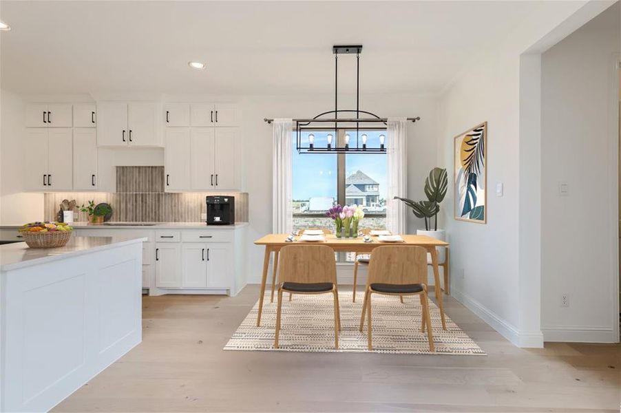 Virtually Staged Photo - Kitchen featuring light wood-type flooring, a notable chandelier, backsplash, hanging light fixtures, and white cabinetry