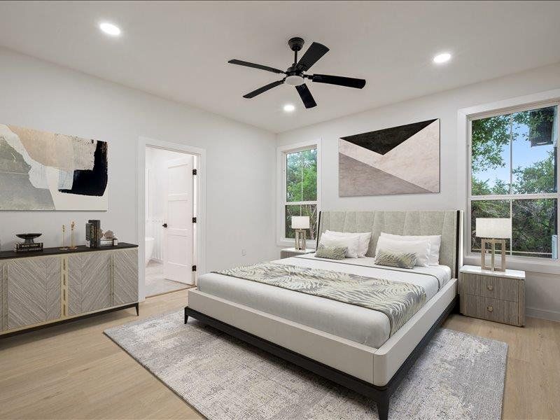 Well-lit room featuring light-toned flooring, two windows with views of greenery, and recessed lighting