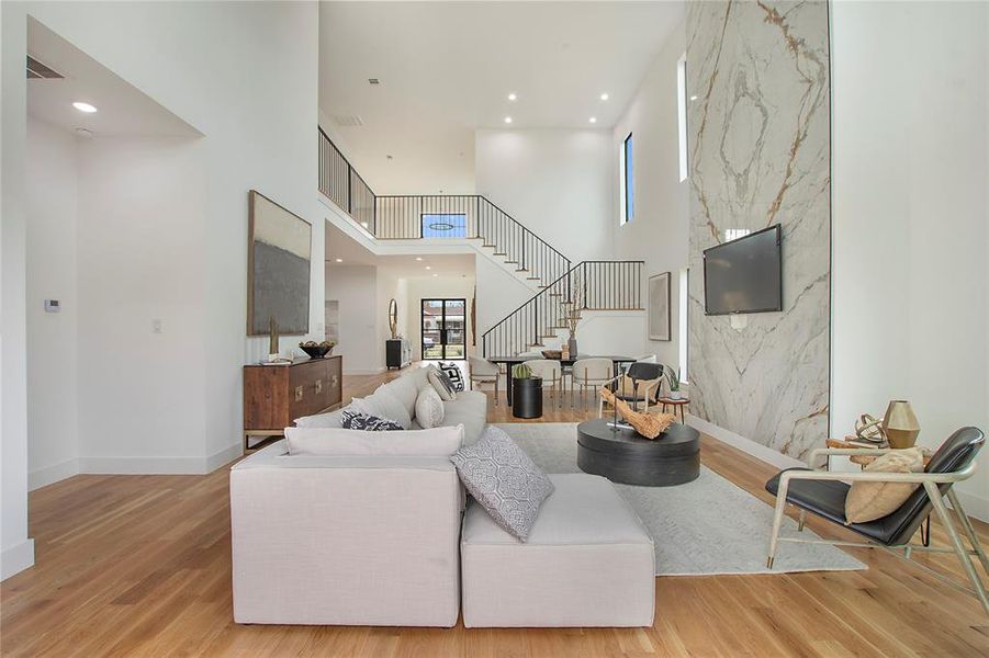 Living room featuring a high ceiling and light hardwood / wood-style floors