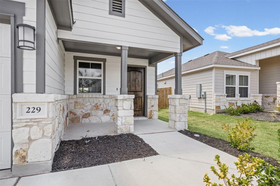 Walkways lead to a covered entryway accented by natural stone and classic wood siding. Walkways lead to a covered entryway accented by natural stone and classic wood siding.