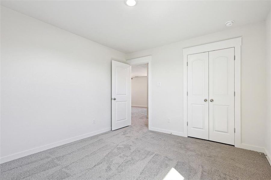 Unfurnished bedroom featuring light carpet and a closet