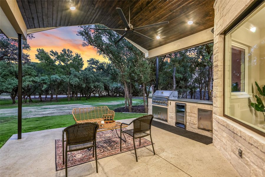 Patio terrace at dusk with exterior kitchen, a patio, ceiling fan, beverage cooler, and a yard Patio terrace at dusk with exterior kitchen, a patio, ceiling fan, beverage cooler, and a yard
