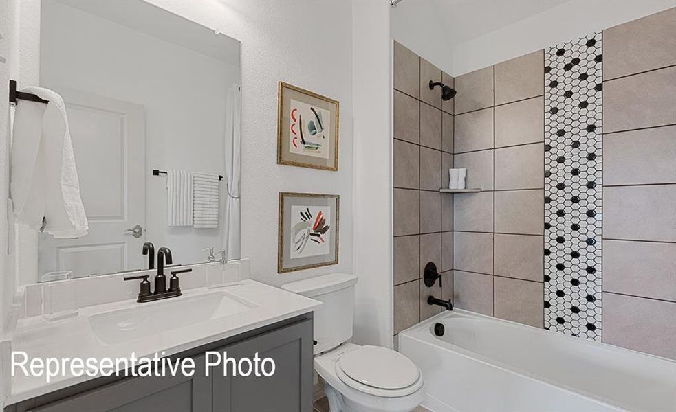 Bathroom featuring a white bathtub, tiled shower surround with a decorative black and white hexagonal accent, dark bronze fixtures, a vanity with a white countertop, and a built-in sink