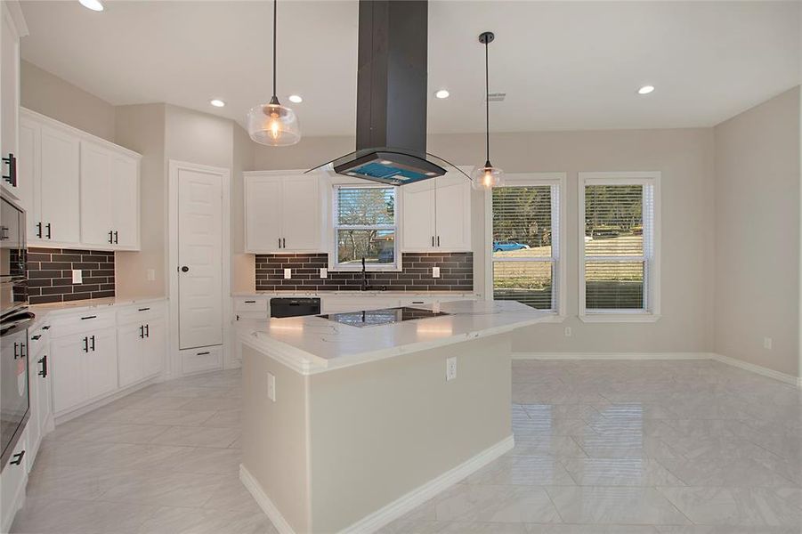 Kitchen with island range hood, a center island, pendant lighting, light stone countertops, and white cabinets