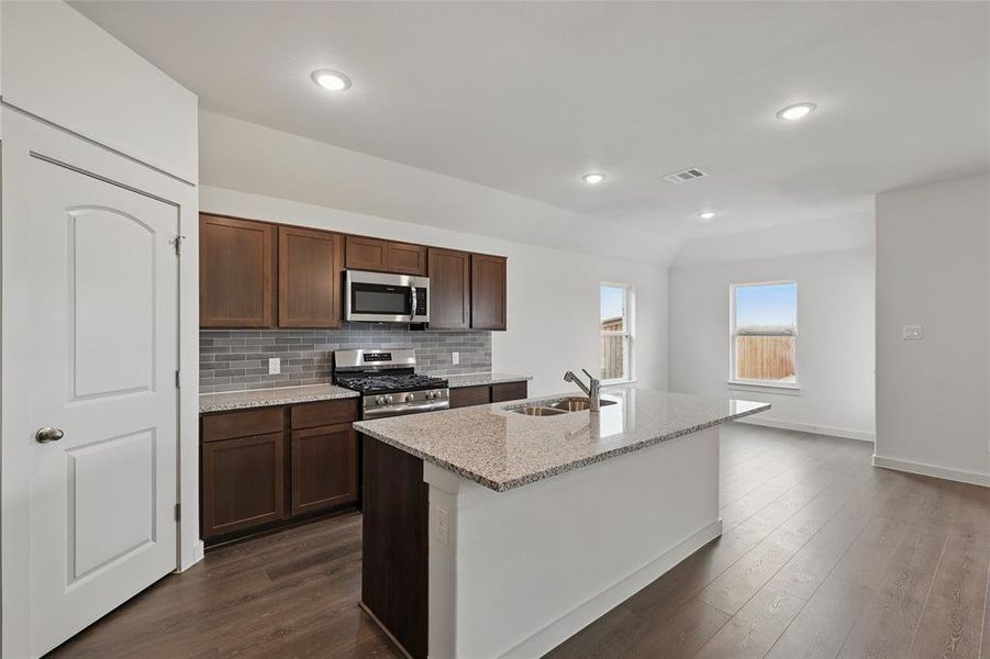Kitchen with light stone counters, stainless steel appliances, dark wood-style flooring, tasteful backsplash, and recessed lighting Kitchen with light stone counters, stainless steel appliances, dark wood-style flooring, tasteful backsplash, and recessed lighting