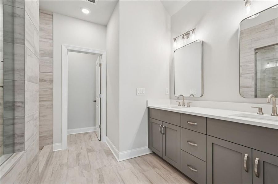 Bathroom with a shower stall, double vanity, and recessed lighting