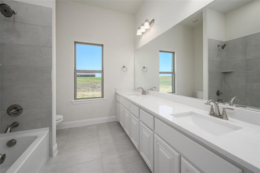 Full bathroom with vanity, tiled shower / bath combo, toilet, and tile patterned floors