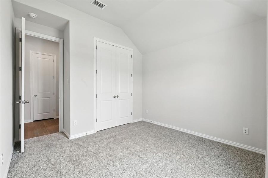 Unfurnished bedroom with vaulted ceiling, carpet flooring, and a closet