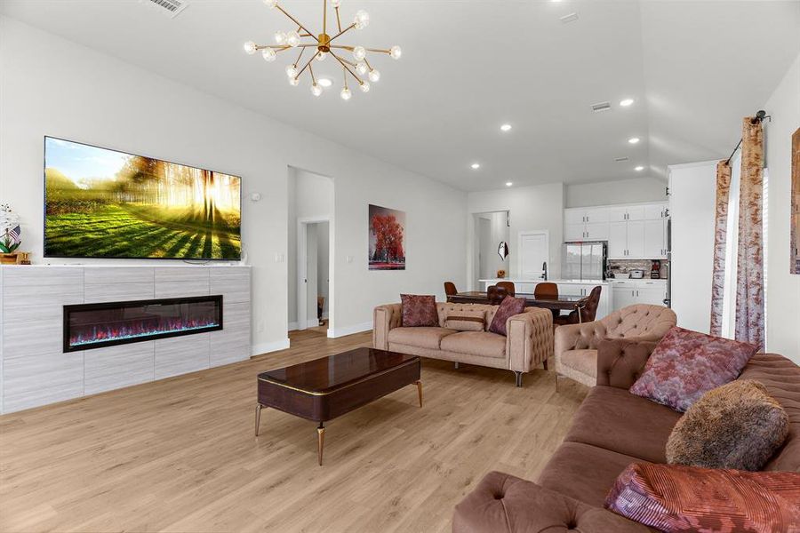 Living area featuring light wood-type flooring, recessed lighting, a chandelier, vaulted ceiling, and baseboards Living area featuring light wood-type flooring, recessed lighting, a chandelier, vaulted ceiling, and baseboards