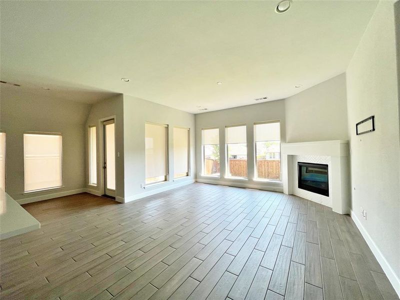 Unfurnished living room featuring a tiled fireplace, light wood-style floors, and recessed lighting Unfurnished living room featuring a tiled fireplace, light wood-style floors, and recessed lighting