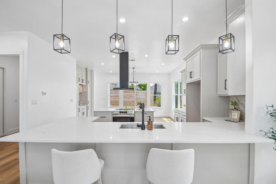 Crisp white cabinetry paired with sleek stone countertops defines this open-concept culinary space. Crisp white cabinetry paired with sleek stone countertops defines this open-concept culinary space.