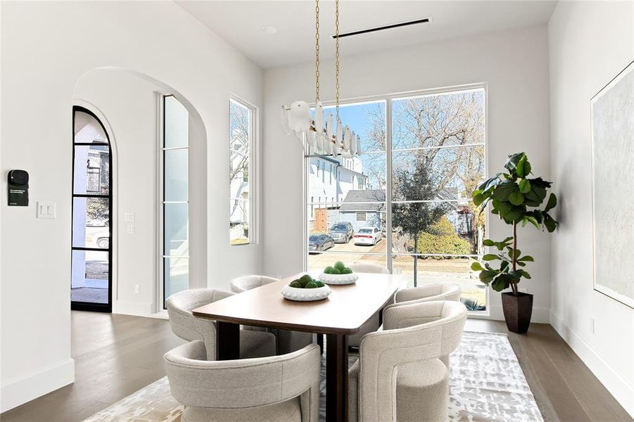 Spacious dining area featuring expansive picture windows, wood-finish flooring, and an arched entryway