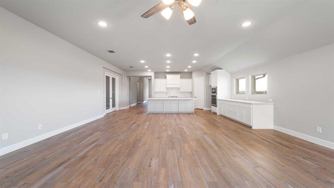 Unfurnished living room with sink, ceiling fan, and light wood-type flooring